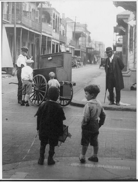 New Orleans La [Street scene showing 4 children and an African American man watching another African American man with a hurdy-gurdy